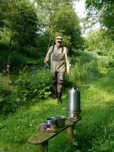 Kelly Kettle Basecamp 1.6L stainless steel camping kettle boiling water outdoors with a fisherman